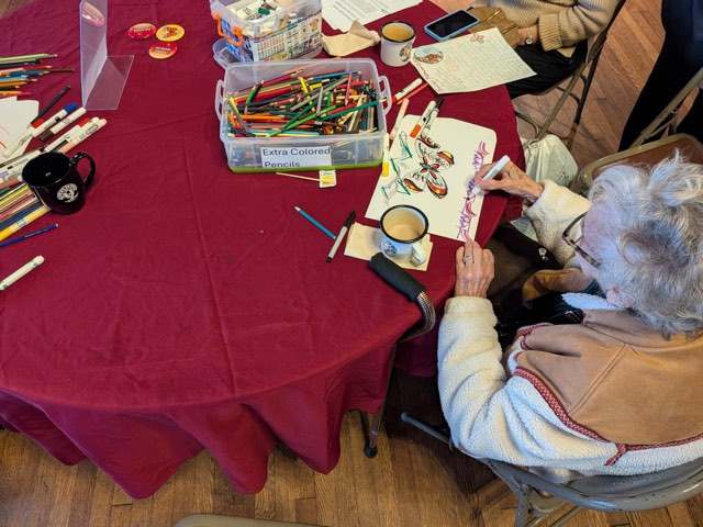 A neighbor decorating an envelope with a butterfly drawing